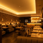 Diners seated in a modern restaurant featuring warm lighting and exposed brick walls.