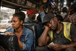 Crowded bus interior with a tired man sleeping and a frustrated woman sitting